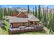 Exterior view of home with deck and outdoor seating surrounded by pine trees and mountain views at 384 Camron Ln, Breckenridge, CO 80424