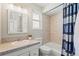 Well-lit bathroom featuring a tiled shower/tub, decorative mirror, and a white toilet at 6975 S Wadsworth Ct, Littleton, CO 80128
