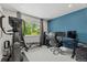 Bright home office with blue accent wall, a large window, exercise machine and comfortable office chair at 6975 S Wadsworth Ct, Littleton, CO 80128