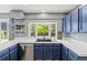 Kitchen boasts a large window over the sink, stainless steel appliances and attractive blue cabinets at 6975 S Wadsworth Ct, Littleton, CO 80128