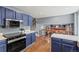Kitchen boasts a connection to the living area with stainless appliances, blue cabinetry, and modern design at 6975 S Wadsworth Ct, Littleton, CO 80128