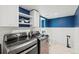 Modern laundry room with sleek appliances, stylish shelving and a convenient sink at 6975 S Wadsworth Ct, Littleton, CO 80128