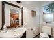 Chic bathroom with a modern sink, toilet, and a framed mirror reflecting the kitchen in the background at 249 S Lincoln St, Denver, CO 80209