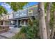 Charming painted brick duplex with a covered front porch, American flag, and lush foliage at 249 S Lincoln St, Denver, CO 80209