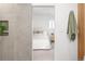 A peek into the well-lit bedroom with neutral decor and bedside table from the en-suite bath at 1755 Ingalls St, Lakewood, CO 80214