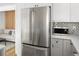 Modern kitchen featuring stainless steel refrigerator, white cabinets, and stylish subway tile backsplash in view to the living space at 1755 Ingalls St, Lakewood, CO 80214