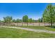 Outdoor horse arena with wooden fence surrounded by green grass and mature trees on a clear, sunny day at 710 Copper Ln # 102, Louisville, CO 80027