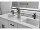 Close-up of a bathroom vanity with double sinks, sleek black faucets, and an illuminated mirror at 17161 E Dewberry Dr, Parker, CO 80134