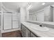 Bright bathroom featuring double sinks, a large mirror, and a glass-enclosed shower at 5202 Reed St, Arvada, CO 80002