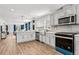 Modern kitchen with stainless steel appliances, light gray cabinets, and open to living area at 5202 Reed St, Arvada, CO 80002