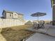 Outdoor patio area with dining set under an umbrella and a spacious yard with a white wooden fence at 5995 Fencerow Pl, Brighton, CO 80601