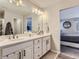 Bathroom featuring double sinks, white cabinets and a view to the Primary Bedroom at 5995 Fencerow Pl, Brighton, CO 80601