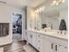 Bathroom featuring double sinks, white cabinets and a doorway to the walk-in closet at 5995 Fencerow Pl, Brighton, CO 80601