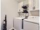 Functional laundry room featuring white washer and dryer units, storage cabinets, and a vacuum cleaner at 5995 Fencerow Pl, Brighton, CO 80601