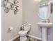 Neat half bathroom features updated fixtures, stylish decorations and sleek pedestal sink at 5995 Fencerow Pl, Brighton, CO 80601