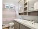 Pink and gray striped bathroom features a double sink vanity, toilet and window for natural light at 6086 W Arizona Ave, Lakewood, CO 80232