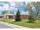 Well-manicured lawn and mature trees surrounding a charming red brick ranch style home with a two-car garage at 6086 W Arizona Ave, Lakewood, CO 80232