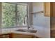 Stainless steel sink with modern faucet beneath a sunlit window offering a verdant view at 20194 Robins Dr, Denver, CO 80249