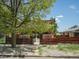 Charming brick home surrounded by mature tree, featuring a decorative wooden fence at 3914 Osage St, Denver, CO 80211