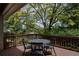 Back deck with wood railing, outdoor seating, and a lovely view of the tree-lined backyard at 12631 W Dakota Dr, Lakewood, CO 80228
