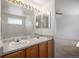 Bathroom featuring double sinks, oak cabinets, and large mirror at 13846 Harrison Dr, Thornton, CO 80602