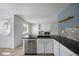 Kitchen with black countertop, stone backsplash, white cabinets, and stainless steel dishwasher and sink at 13846 Harrison Dr, Thornton, CO 80602