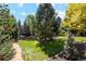 Lush backyard featuring mature trees, manicured lawn, and stone pathways at 7346 S Platte Canyon Dr, Littleton, CO 80128