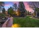 Beautiful backyard with stone accents, lush lawn, mature trees, and landscape lighting at 7346 S Platte Canyon Dr, Littleton, CO 80128