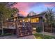 Exterior of home shows wooden stairs, a deck, and access to backyard with illuminated landscape at 7346 S Platte Canyon Dr, Littleton, CO 80128