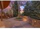 Backyard with a stone patio, mature trees, lovely landscaping, and exterior stairs to a deck at 7346 S Platte Canyon Dr, Littleton, CO 80128