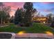 Stunning backyard featuring a stone patio, lush lawn, mature trees, and tasteful landscape lighting at 7346 S Platte Canyon Dr, Littleton, CO 80128