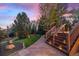 The manicured backyard displays steps to the deck, a winding stone walkway, and lovely, mature trees at 7346 S Platte Canyon Dr, Littleton, CO 80128