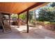 Inviting covered patio featuring stone flooring, wood beams, and outdoor seating area at 7346 S Platte Canyon Dr, Littleton, CO 80128