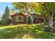 Charming home featuring brick and wood siding, lush lawn, and mature trees at 7346 S Platte Canyon Dr, Littleton, CO 80128