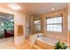Bright bathroom features a glass-enclosed shower, soaking tub, and a large window at 9614 W Powers Cir, Littleton, CO 80123