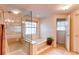 Bright bathroom features a glass-enclosed shower, soaking tub, and a large window at 9614 W Powers Cir, Littleton, CO 80123