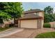 Charming two-story home boasts a large garage, well-manicured lawn, and stone accents at 9614 W Powers Cir, Littleton, CO 80123
