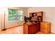 Home office with a large window, wooden desk, and hardwood floors at 9614 W Powers Cir, Littleton, CO 80123