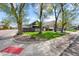 Charming home with a red door, welcoming front porch and green lawn surrounded by mature trees at 800 S Krameria St, Denver, CO 80224