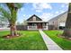 Charming home with a red door, welcoming front porch and green lawn surrounded by mature trees at 800 S Krameria St, Denver, CO 80224