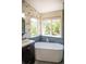 Bright bathroom featuring a sleek soaking tub and verdant outdoor views at 3314 Astorbrook Cir, Highlands Ranch, CO 80126
