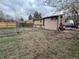 A home's spacious backyard with chain link and wood fencing, grass and dirt, on an overcast day at 5363 W 4Th Ave, Lakewood, CO 80226