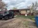 A single story home with red trim and mature trees, with a black Jeep parked in the unpaved driveway at 5363 W 4Th Ave, Lakewood, CO 80226
