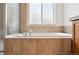 Large soaking tub surrounded by neutral tile, a bright window, and chrome faucet at 2130 Chestnut Cir, Erie, CO 80516