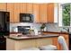 Kitchen featuring black appliances, wood cabinetry, tiled backsplash and a breakfast bar with stools at 2130 Chestnut Cir, Erie, CO 80516