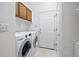 Functional laundry room with washer, dryer, upper cabinets, and linoleum floors at 2130 Chestnut Cir, Erie, CO 80516