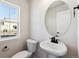 Small powder room with pedestal sink and oval mirror at 8588 Eagle River St, Littleton, CO 80125