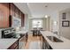 Contemporary kitchen with dark wood cabinetry, stainless appliances, and a view of the dining area at 2426 Welton St, Denver, CO 80205