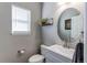 Well-lit powder room with a modern sink, round mirror, and a charming floating shelf at 16590 Hitching Post Cir, Parker, CO 80134