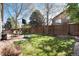 Large fenced backyard includes a brick paver patio, lawn, and shade trees at 1374 Spotted Owl Way, Highlands Ranch, CO 80129